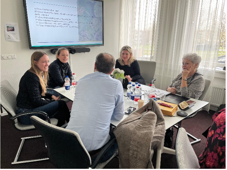 5 medewerkers rond vergadertafel